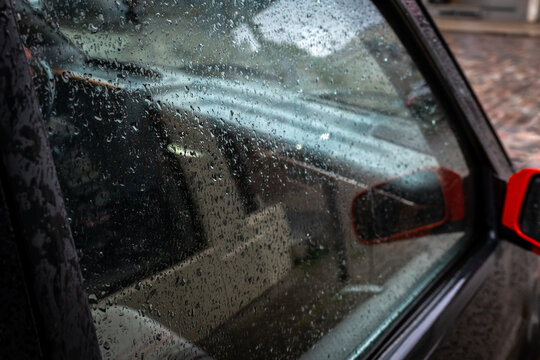 Raindrops Cover a Car Window During Wet Urban Traffic