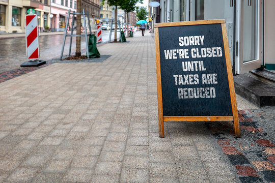 SORRY WE'RE CLOSED UNTIL TAXES ARE REDUCED Sign on Rainy City Sidewalk