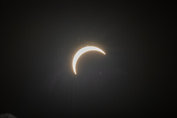 Partial solar eclipse captured as the Moon passes in front of the Sun, creating a striking crescent shape against the dark sky. An astronomical event photographed during daylight. © KjLOWRYPHOTOGRAPHY