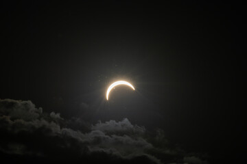 Partial solar eclipse captured as the Moon passes in front of the Sun, creating a striking crescent shape against the dark sky. An astronomical event photographed during daylight. © KjLOWRYPHOTOGRAPHY
