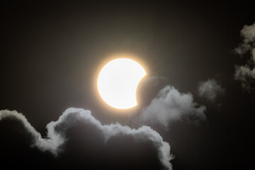 Partial solar eclipse captured as the Moon passes in front of the Sun, creating a striking crescent shape against the dark sky. An astronomical event photographed during daylight. © KjLOWRYPHOTOGRAPHY