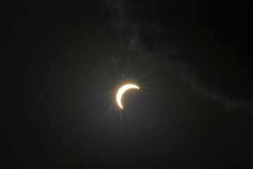 Partial solar eclipse captured as the Moon passes in front of the Sun, creating a striking crescent shape against the dark sky. An astronomical event photographed during daylight. © KjLOWRYPHOTOGRAPHY