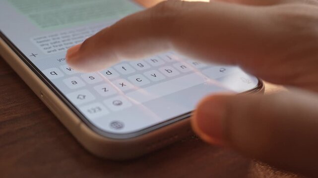 Woman's hand chatting and typing on a smartphone, macro closeup. Unrecognisable human typing a text message, tapping the touchscreen keyboard using the WhatsApp application, a social media.