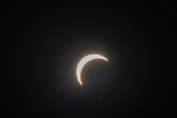 Partial solar eclipse captured as the Moon passes in front of the Sun, creating a striking crescent shape against the dark sky. An astronomical event photographed during daylight. © KjLOWRYPHOTOGRAPHY