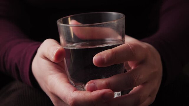 Close-up of hands holding a glass of water during a calm consultation, likely in a psychologist or doctors office.