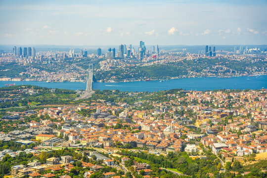 Aerial view of Istanbul cityscape featuring Bosphorus Bridge, modern skyscrapers, and residential areas under a clear blue sky