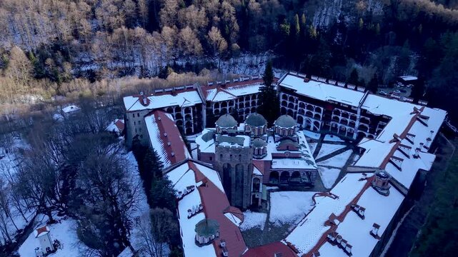 Aerial view of Rila Monastery in winter with snow-covered rooftops and historic architecture in Rilski manastir, Kyustendil, Bulgaria.