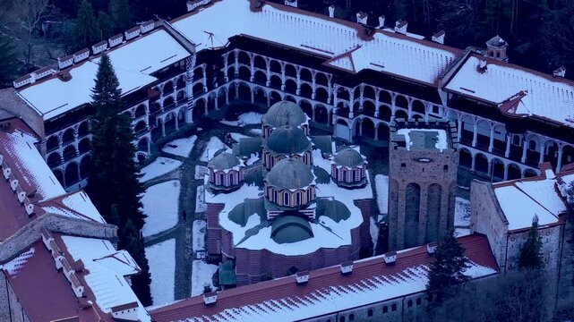 Aerial view of the snow-covered Rila Monastery with its historic domes and courtyard in Rilski manastir, Kyustendil, Bulgaria.