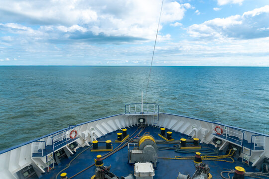 Forward bow deck of a passenger ferry equipped with mooring winch, heavy ropes, bollards, fairleads and safety gear overlooking open water. Detailed maritime scene represents ship handling, mooring op