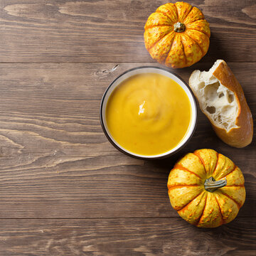 Overhead pumpkin soup bowl with crusty bread and mini pumpkins