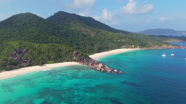 Aerial view of Anse Reunion beach with turquoise waters, white sand, and lush green hills on the coast of Anse Reunion, La Digue, Seychelles.