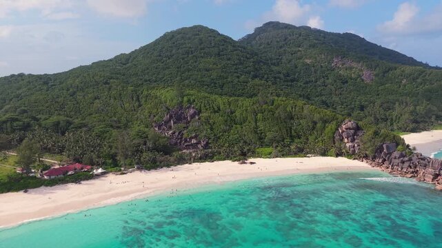 Aerial view of Anse Reunion beach with turquoise water, white sand, and lush green hills in Anse Reunion, La Digue, Seychelles.