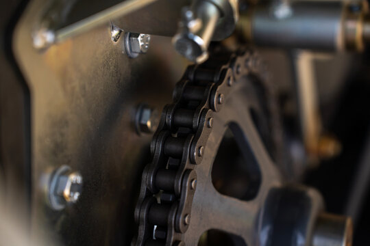 Industrial heavy roller chain installed on gear sprocket wheel transmission mechanism inside machinery.