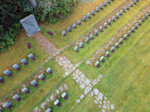 Aerial view of military cemetery with rows of gravestones, stone pathways, and green grass in Muhos, North Ostrobothnia, Finland.