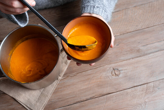 Woman's hands ladling soup into bowl