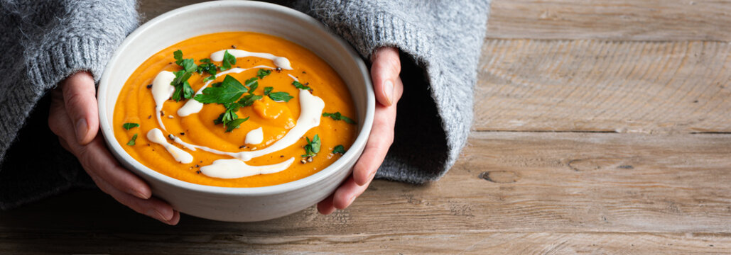 Bowl of pumpkin soup in woman hands