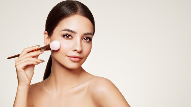 Portrait beautiful young woman with clean fresh skin. Model with cosmetic makeup brush. Healthy clean fresh skin natural make up beauty eyes