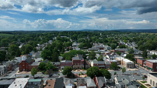Aerial view of the historic town of Manheim with its charming brick buildings, lush green trees, and quiet streets under a bright sky in Manheim, Pennsylvania, United States.