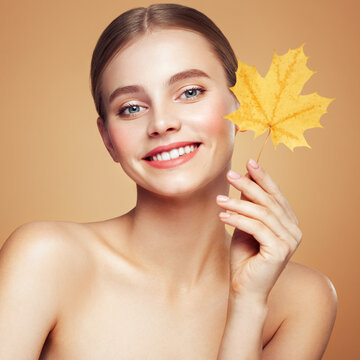 Portrait of beautiful young woman with autumn leaves. Healthy clean fresh skin natural make up beauty eyes