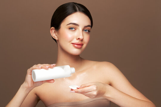 Young girl holds cotton pad while cleansing face with cosmetic milk. Skin care removal of makeup cleansing. Basic facial skin care