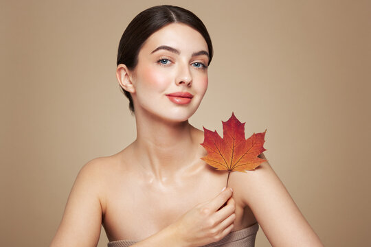 Portrait of beautiful young woman with autumn leafs. Healthy clean fresh skin natural make up beauty eyes