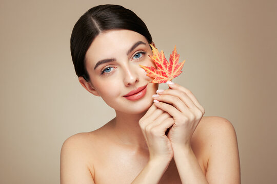 Portrait of beautiful young woman with autumn leafs. Healthy clean fresh skin natural make up beauty eyes