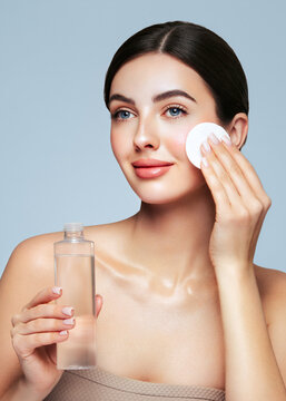 Young girl holds cotton pad while cleansing face with cosmetic milk. Skin care removal of makeup cleansing. Basic facial skin care