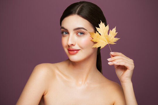 Portrait of beautiful young woman with autumn leafs. Healthy clean fresh skin natural make up beauty eyes