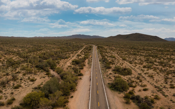 Aerial view of Arizona 86 highway stretching through the Sonoran Desert with saguaro cacti, scrub brush, and distant mountains in Pima County, Arizona, United States.