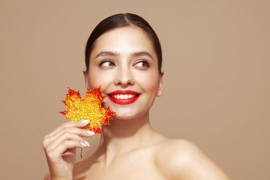 Portrait of beautiful young woman with autumn leafs. Healthy clean fresh skin natural make up beauty eyes