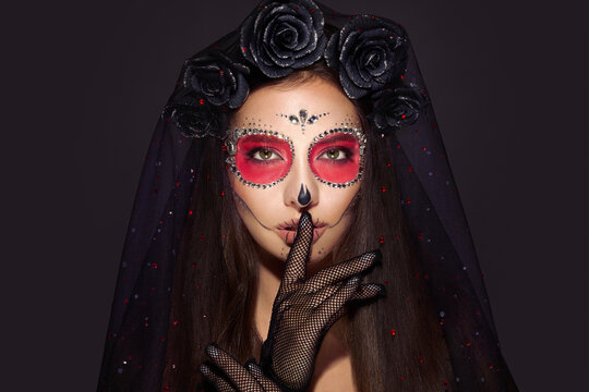 Portrait of a woman with sugar skull makeup over black background. Halloween costume and make-up. Portrait of Calavera Catrina