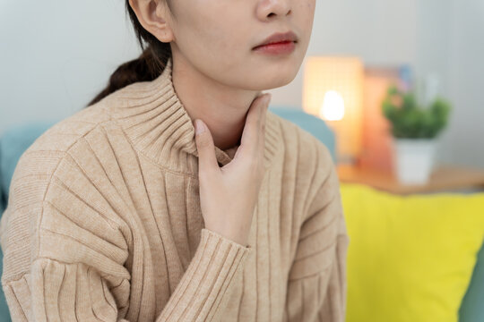 Asian woman put on neck due to a sore throat. female tonsillitis causes a inflammation. treated by taking water, taking antibiotics, consult a doctor, virus, corona virus, Influenza, flu