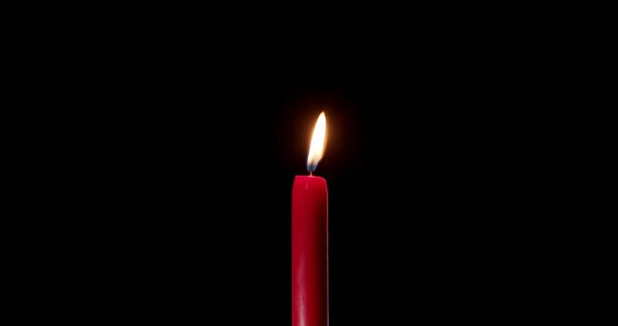 Tall red candle burning steadily in a quiet dark room. The clean flame of this wax candle cuts through shadows. This glowing candle symbolizes faith, peace, and festive overlay design.