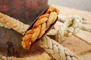 Obraz premium Heavy-duty mooring rope with a rusty metal thimble hitched on a harbor bollard. Port infrastructure and maritime concept.