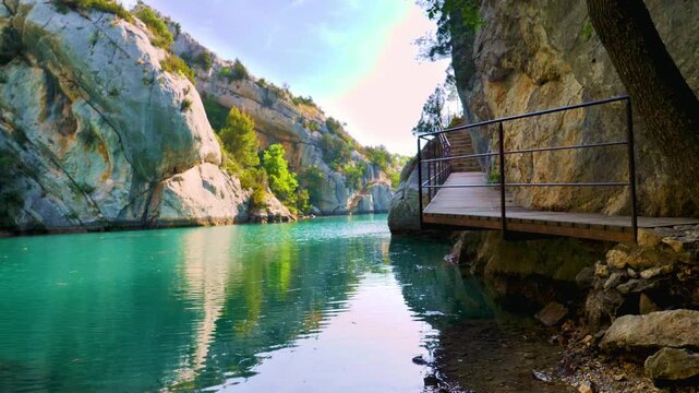 wooden walkway along turquoise river canyon with rocky cliffs in verdon gorge france