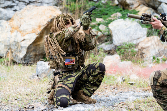 Soldiers in camouflage perform training drills in a natural outdoor setting