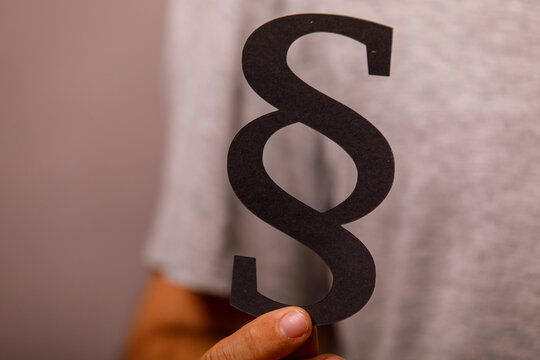 A person holds a black paper section sign, symbolizing law, justice, and legal matters.