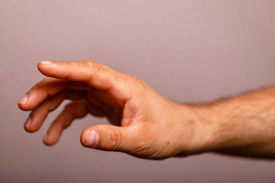 Close-up of a human hand reaching forward against a simple, neutral background.