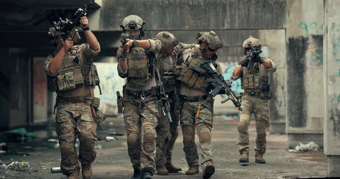 Military team carries wounded teammate to safety while covering the area with rifles