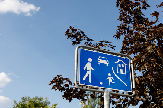 Blue road sign indicating a residential area with symbols for people, child, car, and house under bl