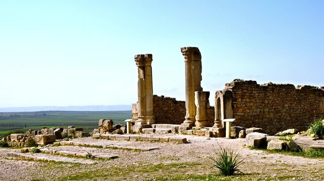 ancient roman ruins with stone columns under clear sky overlooking countryside landscape in volubilis morocco