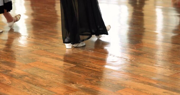 Dancers practicing Standard-style dance moves on the floor.