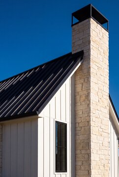 Chopped Limestone Chimney Rising Above Black Standing Seam Metal Roof