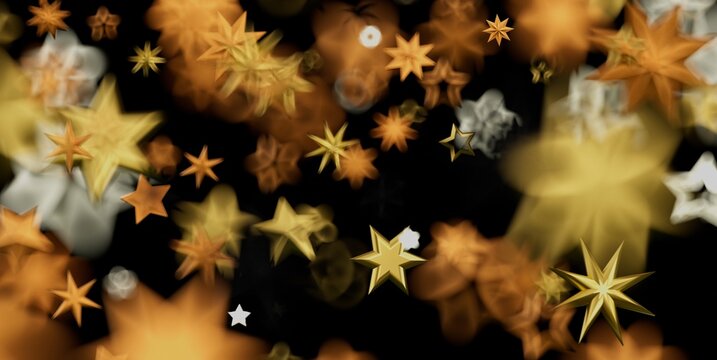 Abstract background with sparkling golden and orange stars, some in focus, some blurred, on black.