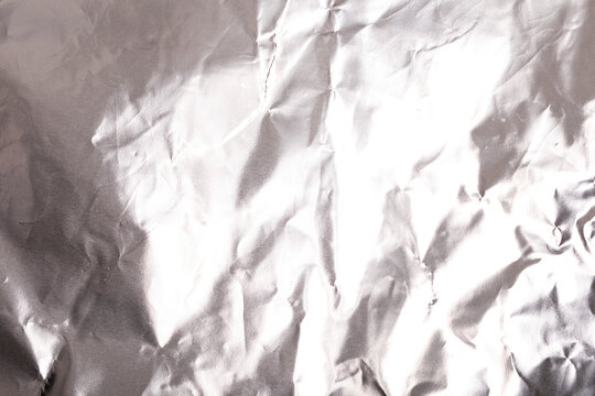 Close-up view of a shiny, wrinkled silver aluminum foil surface, perfect for backgrounds.