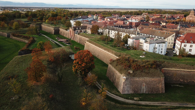 Aerial view of the historic Vauban walled city of Neuf-Brisach featuring stone fortifications, autumn trees, and traditional rooftops in Neuf-Brisach, Grand Est, France.