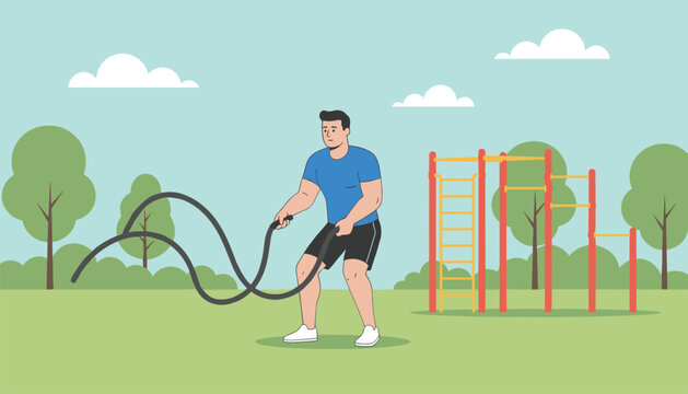 Athletic man working out with heavy battle ropes in a public park with fitness equipment and trees.