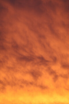 Red, orange and golden dawn light illuminates textured clouds, creating a dramatic natural sky background with copy space