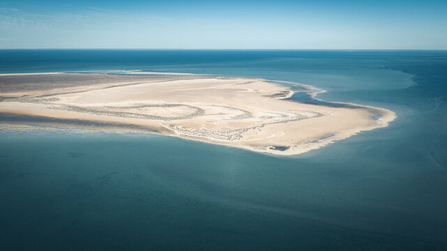 Aerial view of intricate sand patterns and turquoise waters along the coastline in Denham, Western Australia, Australia.