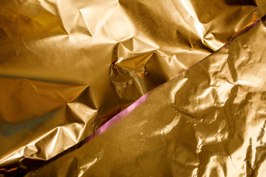 Textured background of crumpled golden material with subtle reflections and a diagonal split.